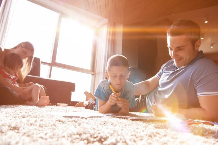 Happy Young Family Playing together at Home on the Floor using a Tablet and a Childrens Drawing Set Happy Young Family Playing together at Home on the Floor using a Tablet and a Childrens Drawing Set